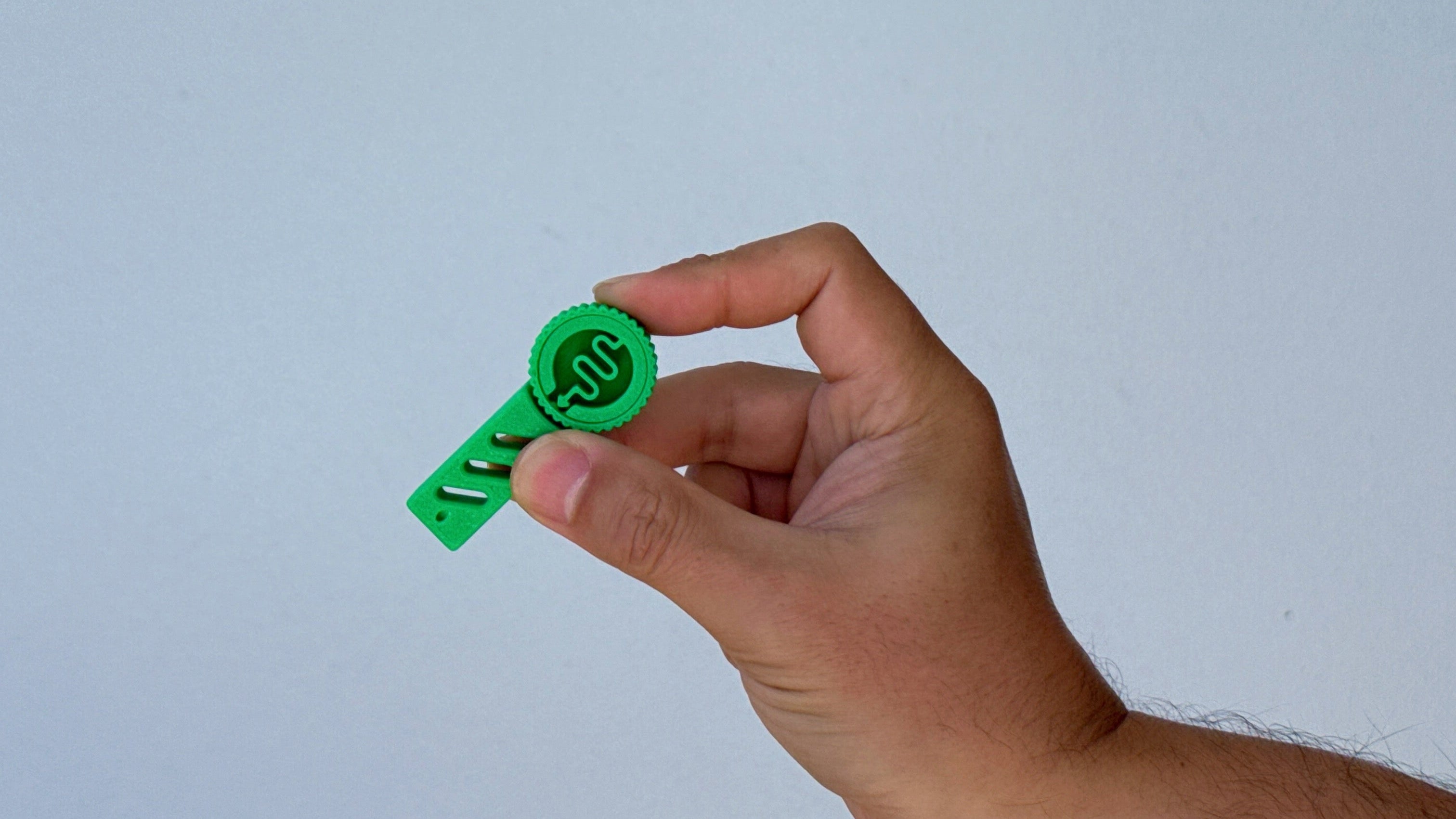 Hand holding a small green fidget toy against a white background.