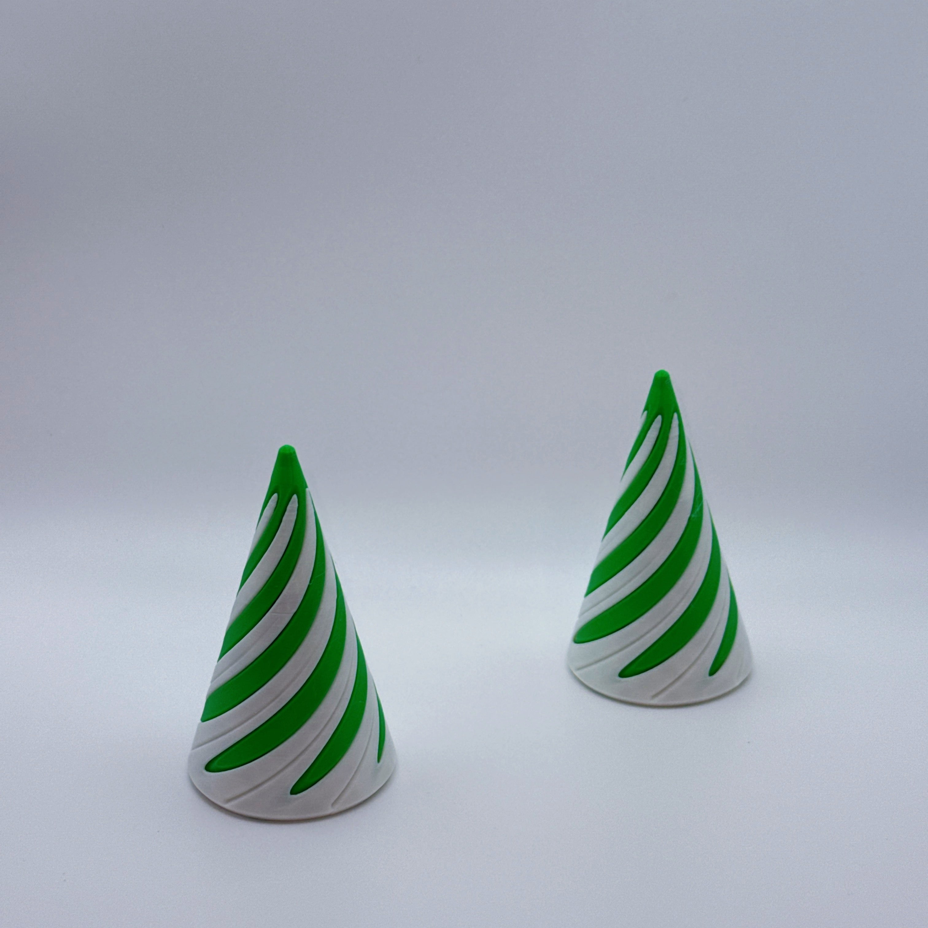 Two green and white large Spirally striped cone-shaped fidget toys on a gray background