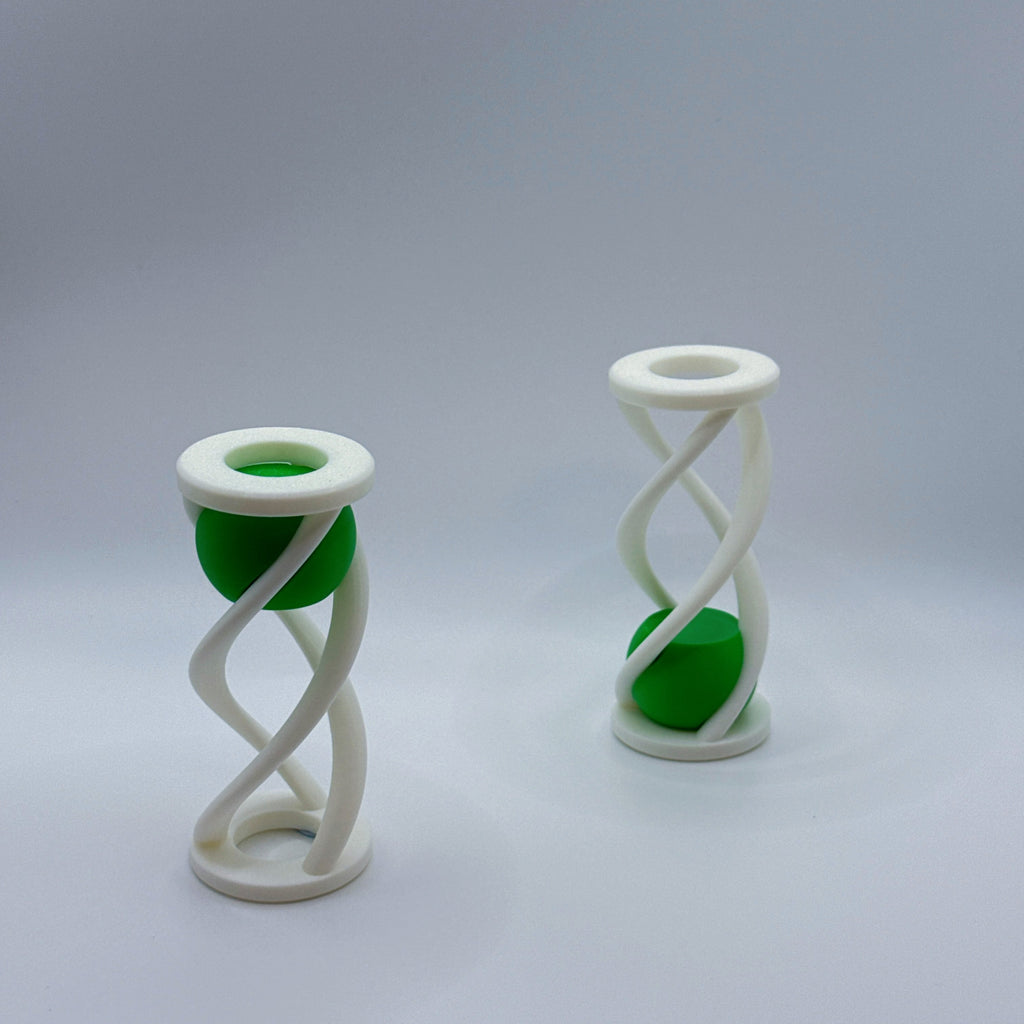 Two white Impossiball spiral-shaped fidget toys with a green ball on a gray background.