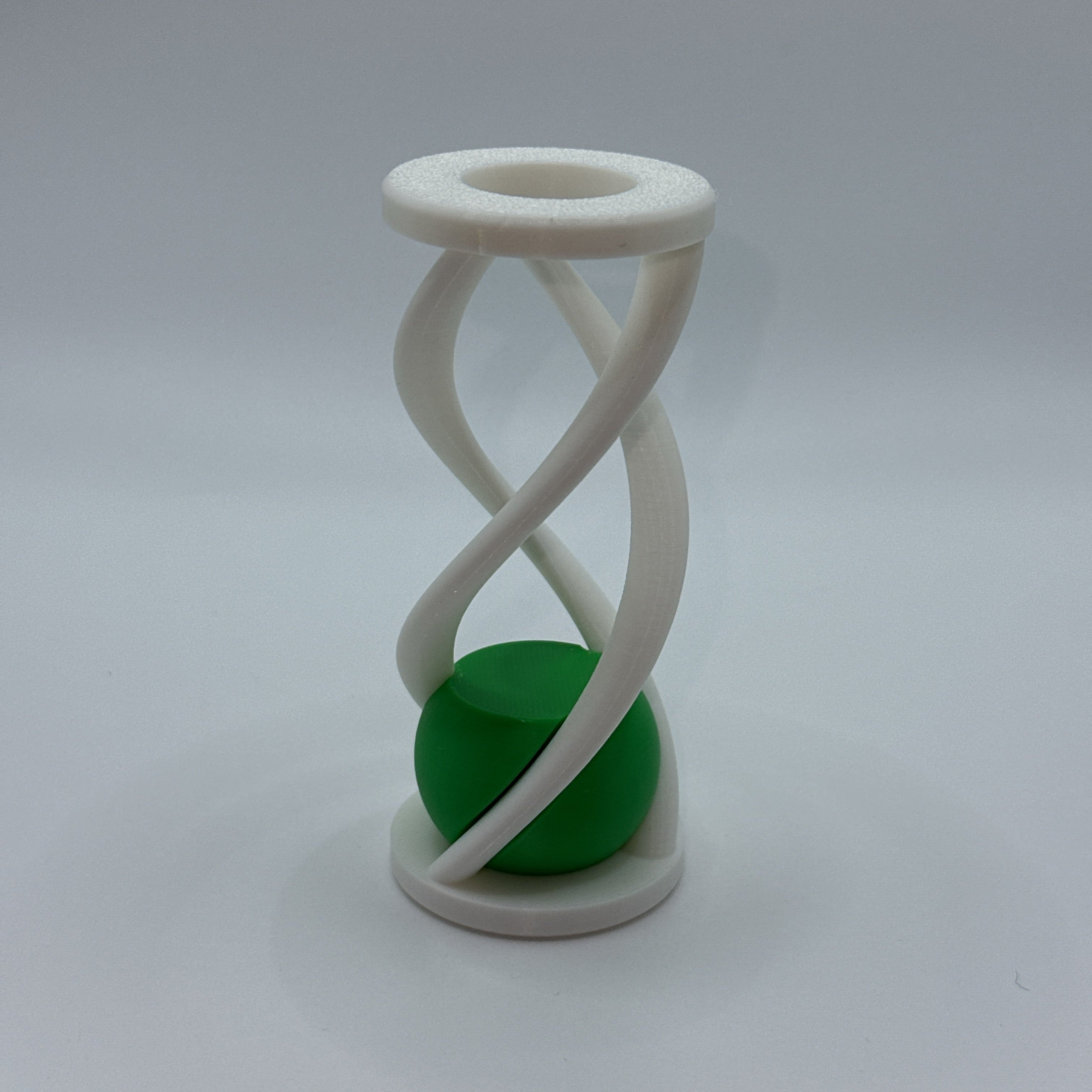 White Impossiball spiral fidget toy with a green ball on a white background