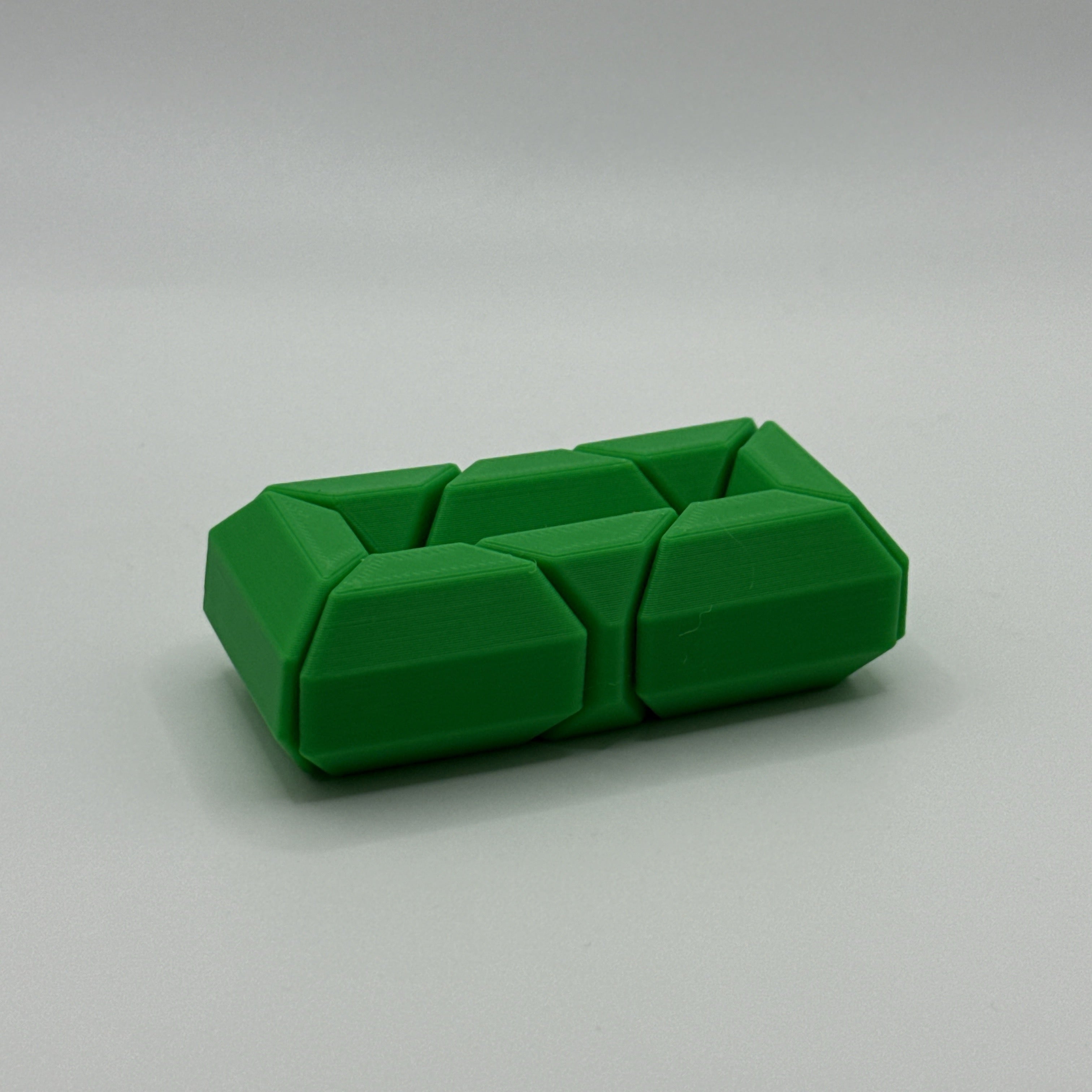 Green Infinite Twist hexagon-shaped fidget toy on a gray background