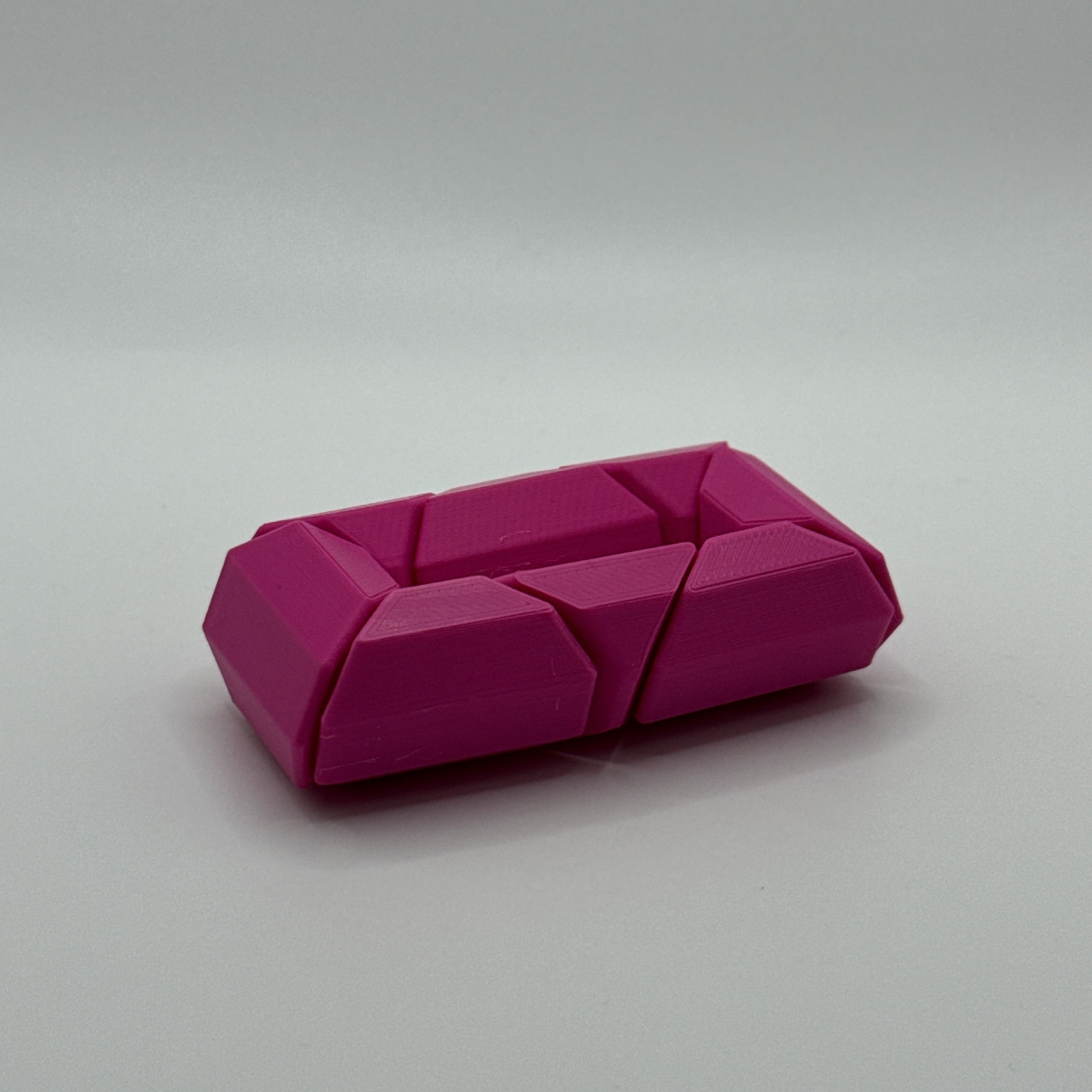 Magenta Infinite Twist hexagon-shaped fidget toy on a gray background