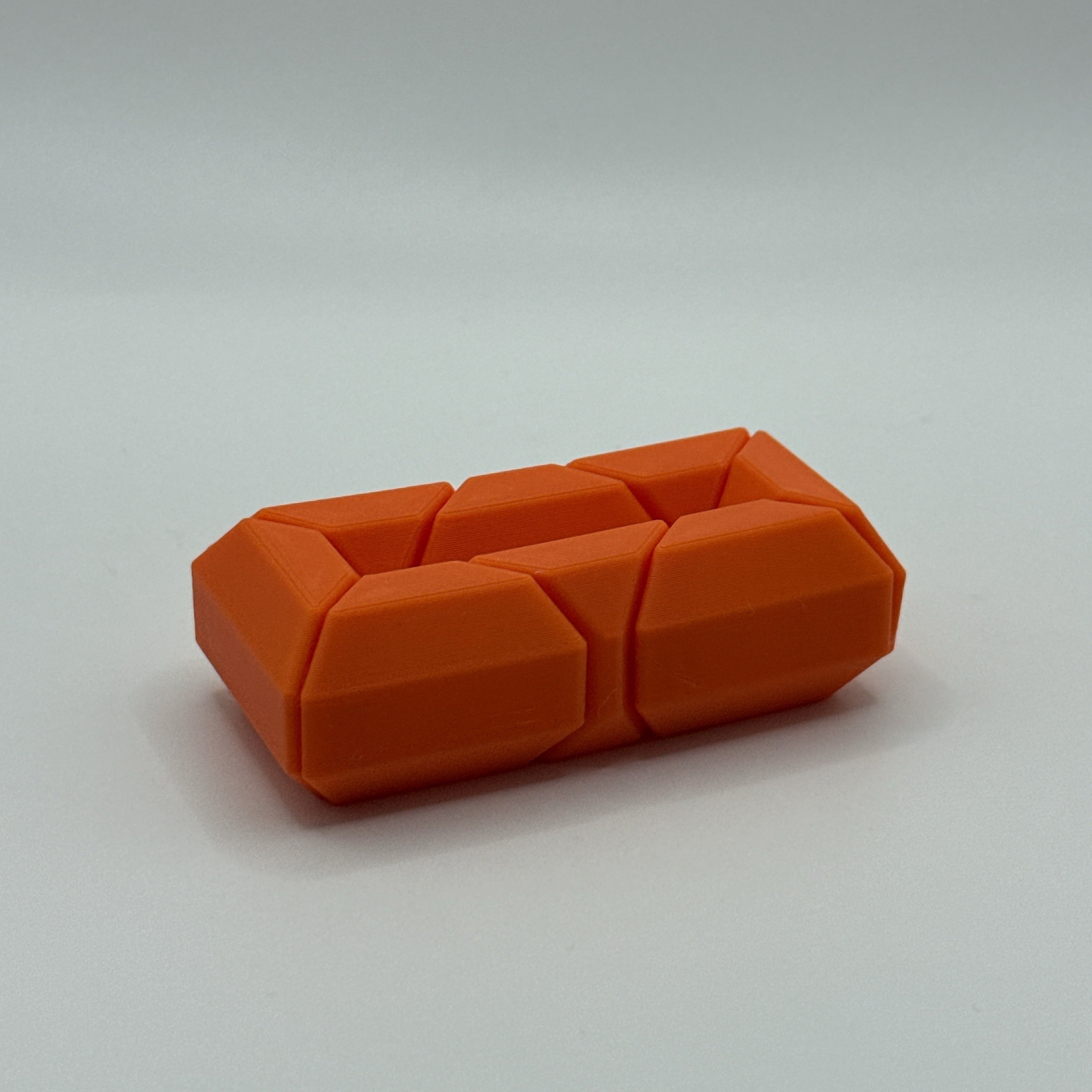 Orange Infinite Twist hexagon-shaped fidget toy on a white background