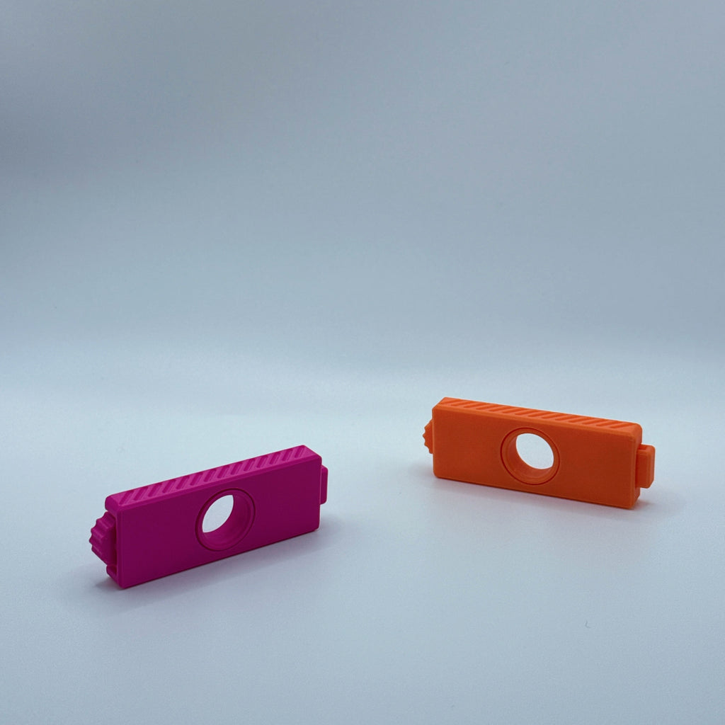 Magenta and orange Fusion Fidget fidget toys on a gray backgound
