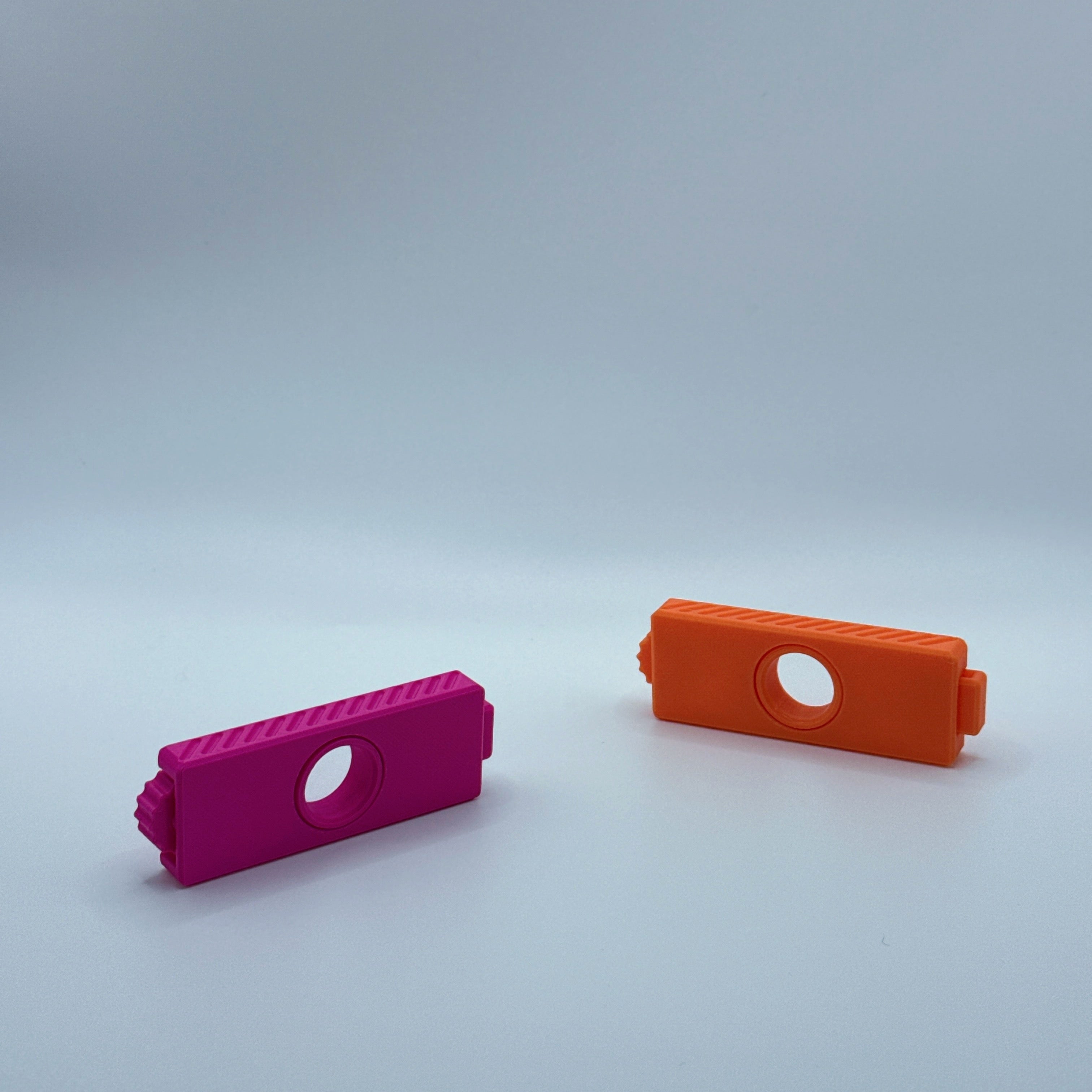 Magenta and orange Fusion Fidget fidget toys on a gray backgound