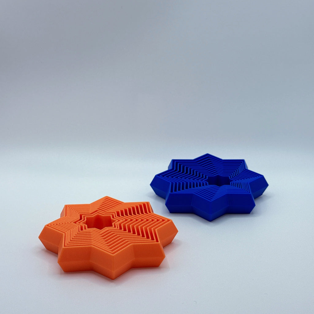 Orange and blue Supernova star-shaped fidget toys on a light gray background.