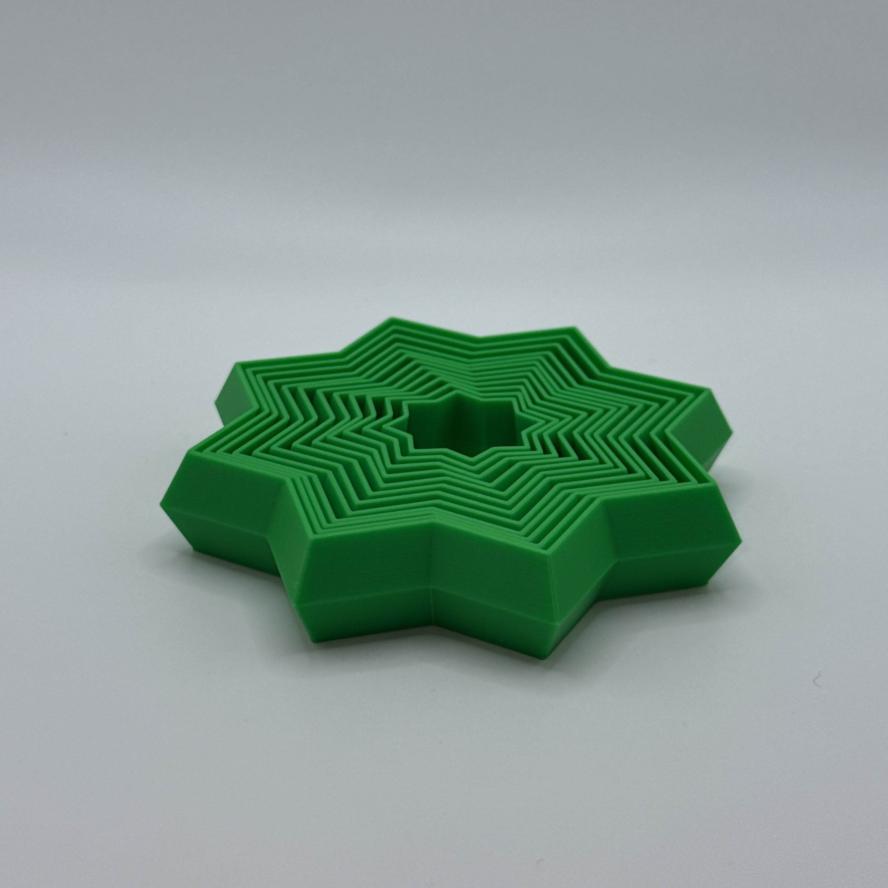 Green Supernova star-shaped geometric fidget toy on a gray background