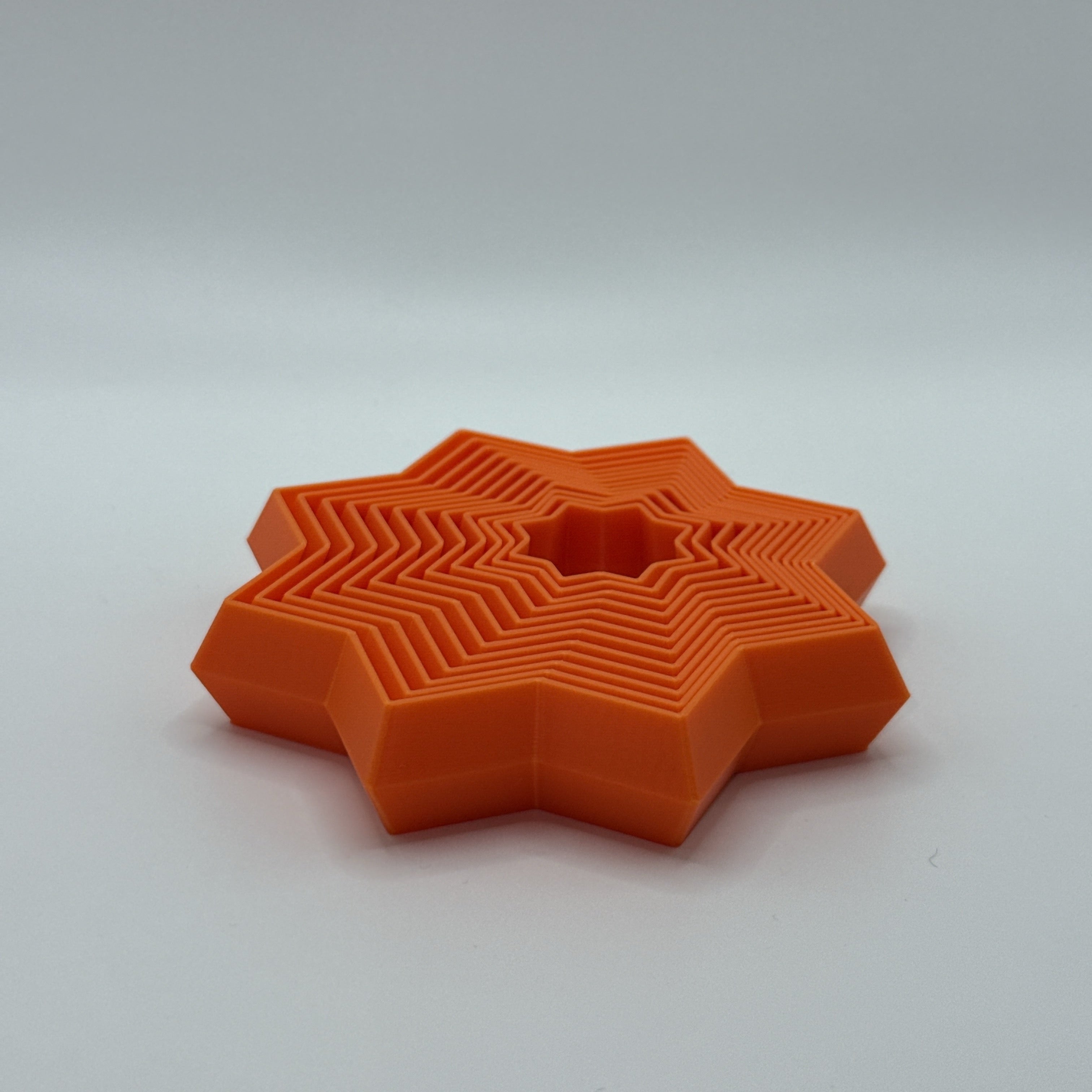 Orange Supernova star-shaped geometric fidget toy on a white background