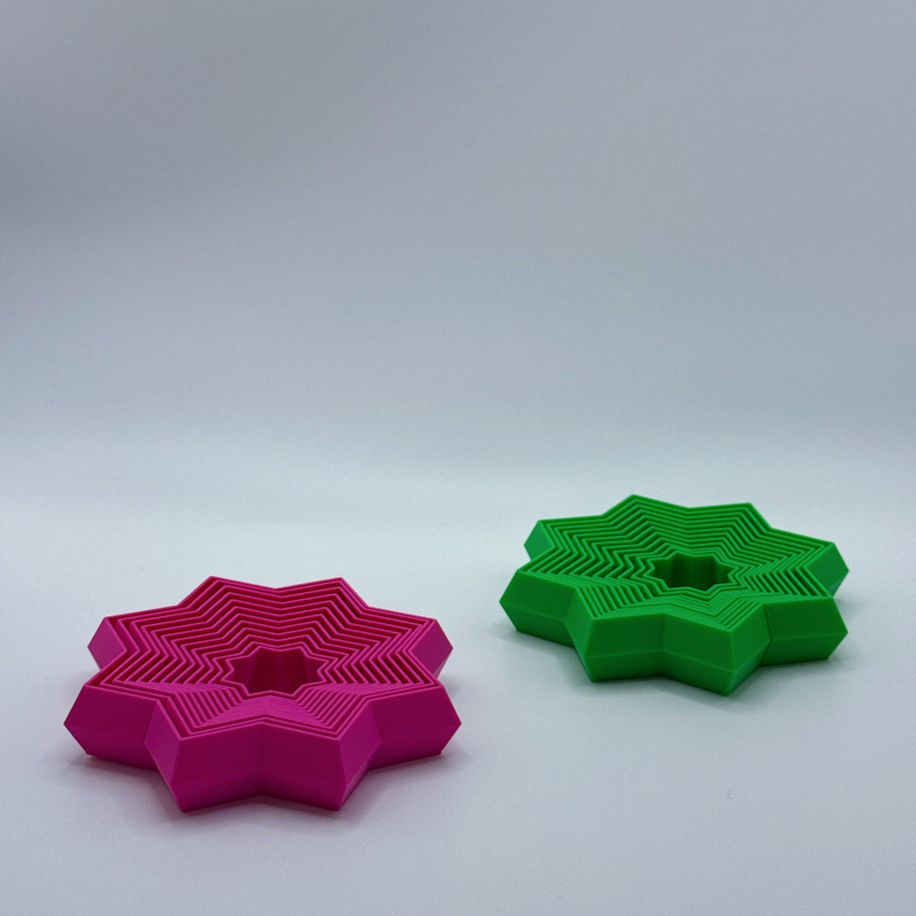 Magenta and green Supernova star-shaped fidget toys on a gray background